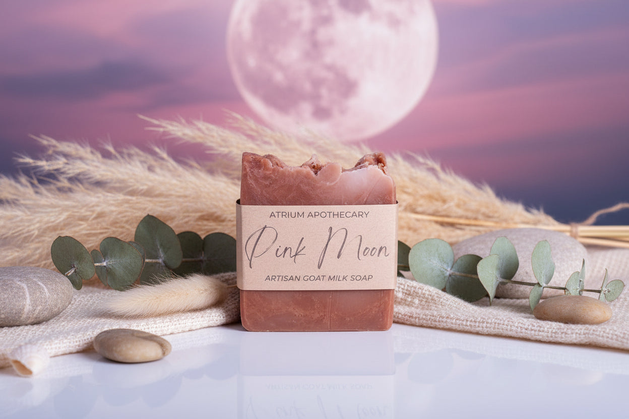 A bar of artisan goat milk soap with a beige to brown ombre design, wrapped in a kraft paper band labeled 'Pink Moon'