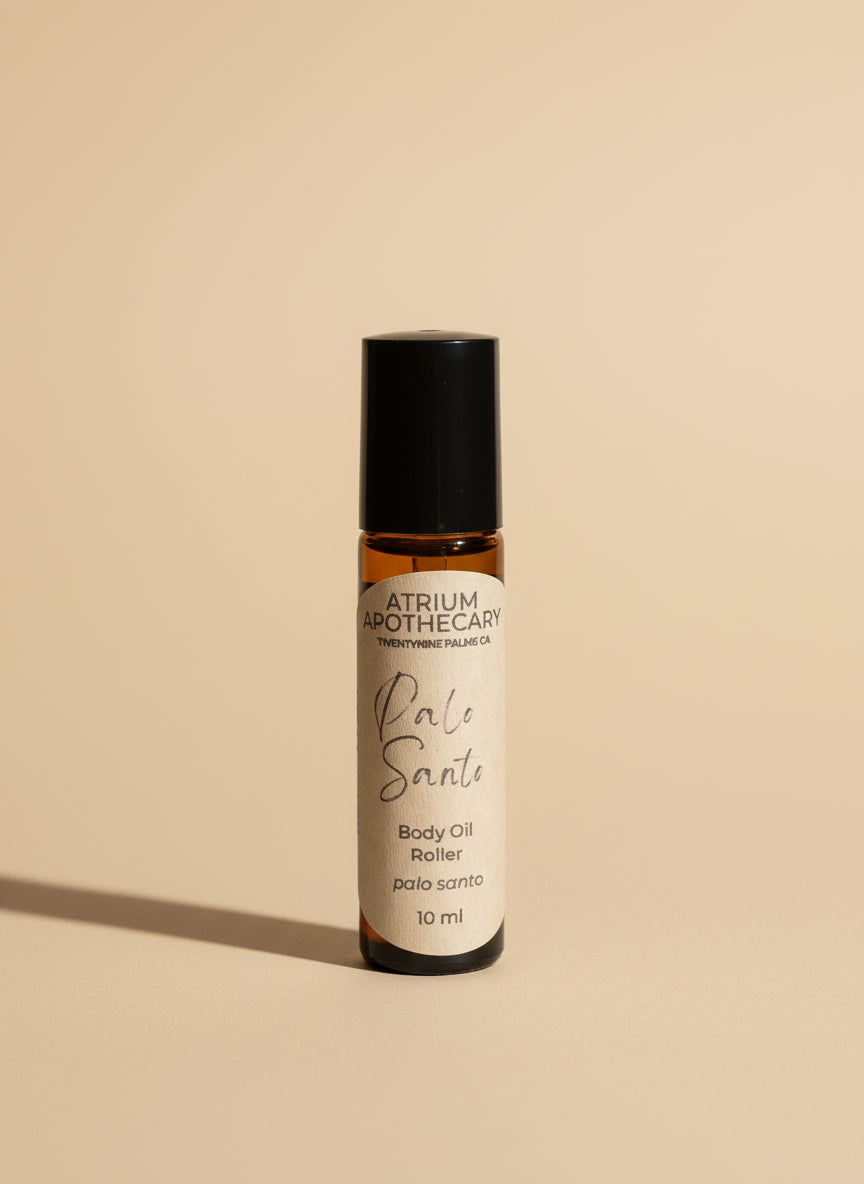 Atrium Apothecary Palo Santo body oil roller on a white surface with a blurred background
