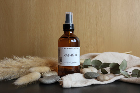 Brown spray bottle labeled 'Kashmir' on a wooden surface with decorative elements.