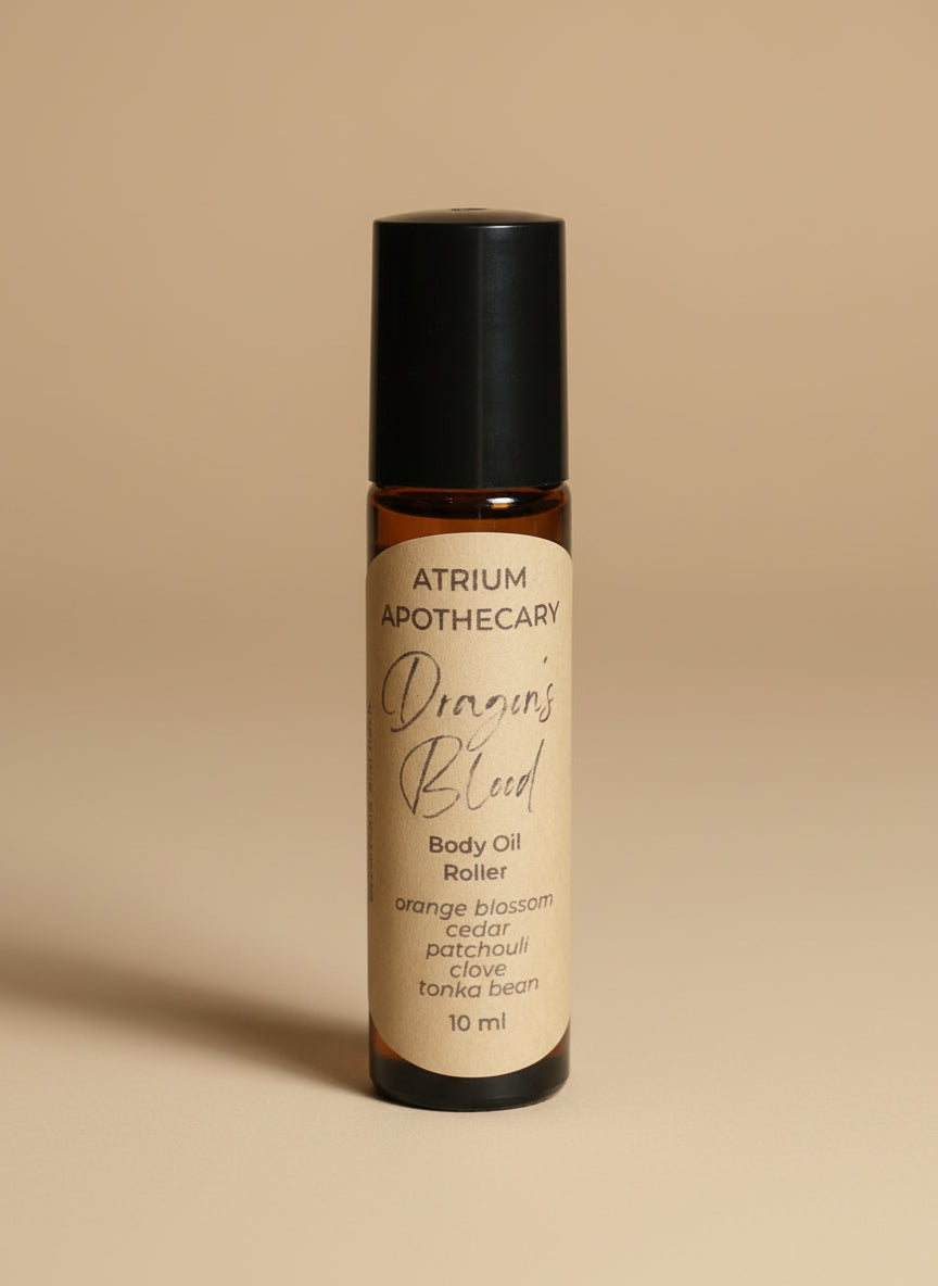 Atrium Apothecary Dragon's Blood body oil roller on a white surface with a blurred background