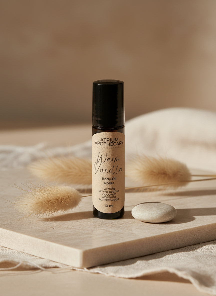A black rollerball bottle of body oil with a label that reads 'Atrium Apothecary Warm Vanilla Body Oil Roller 10ml'.