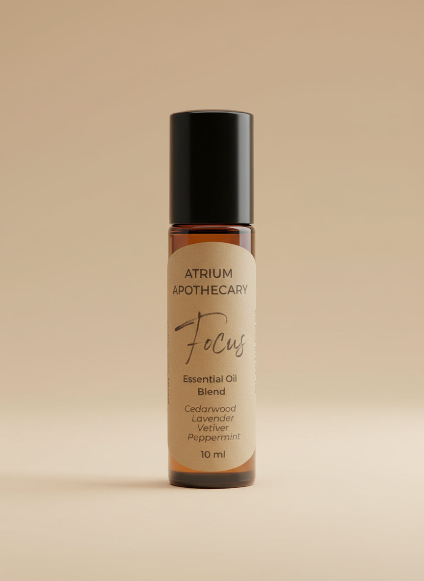 Atrium Apothecary Focus essential oil blend bottle on a white surface with a plant in the background.