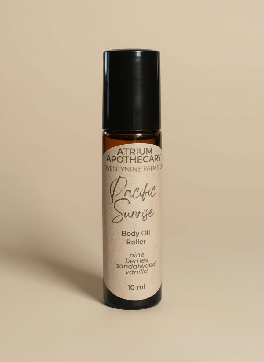 Body oil roller bottle labeled 'Pacific Sunrise' by Atrium Apothecary on a black background