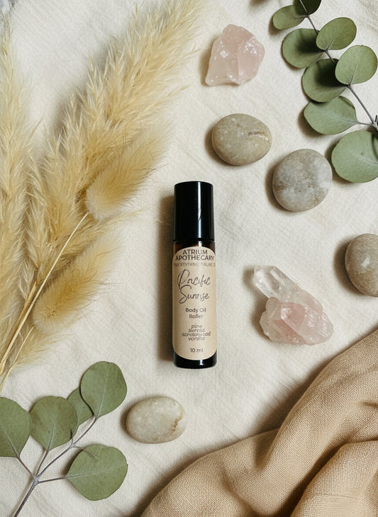 Body oil roller bottle labeled 'Pacific Sunrise' by Atrium Apothecary on a white surface.