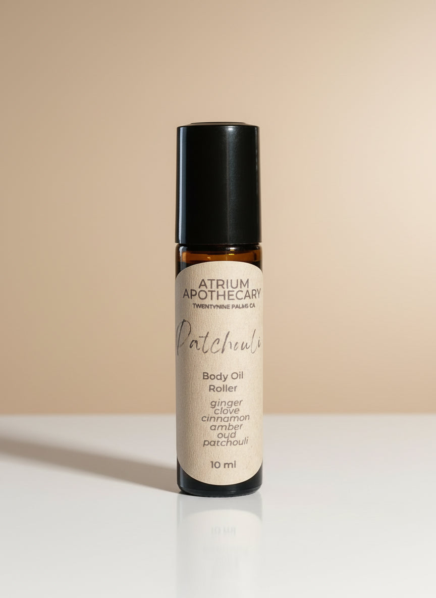 Atrium Apothecary body oil roller bottle on a white surface with a neutral background