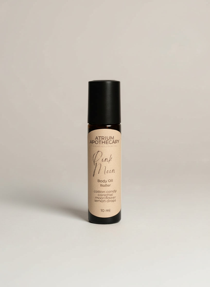 Body oil roller bottle with black cap and beige label on a white background